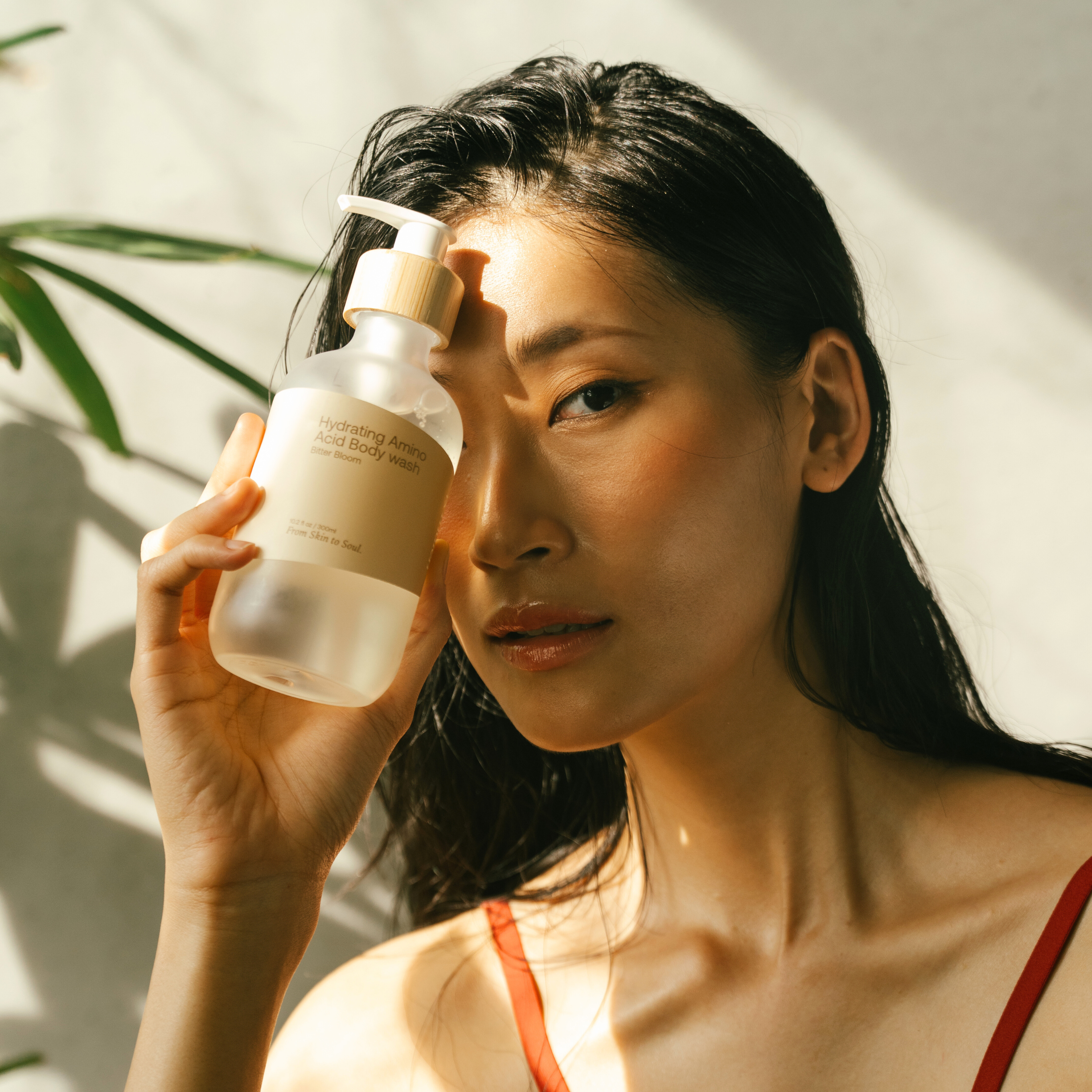 Woman holding a bottle of bodywash product with a natural background